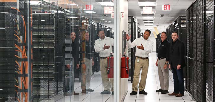 Three men walking through data center looking at server racks