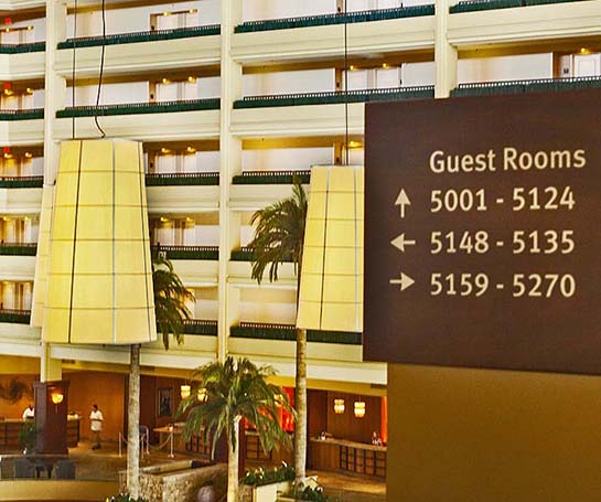 Image of hotel hallway overlooking open hotel lobby with a guest room directional sign