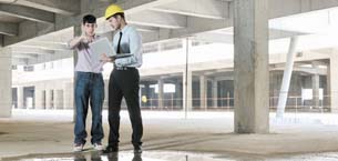 Two men looking at a laptop in a construction site