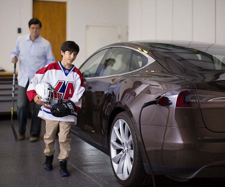 Father and son in the garage, while the electric vehicle is charging