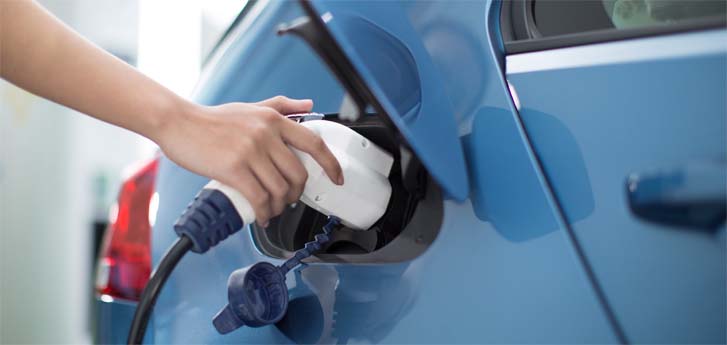 Hand holding electric vehicle pump inserted into car