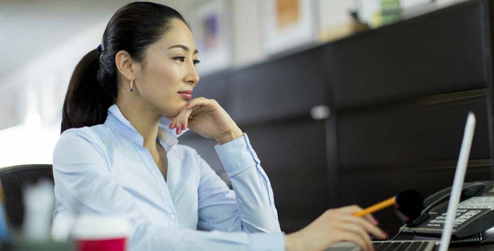 Asian woman smiling and looking at her laptop