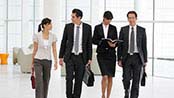 4 office employees walking together down a hallway