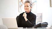 Older woman employee sitting at her desk and looking at her laptop