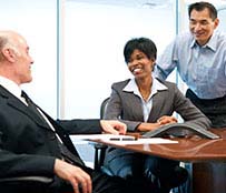 Two men and a woman smiling and having a discussion at work