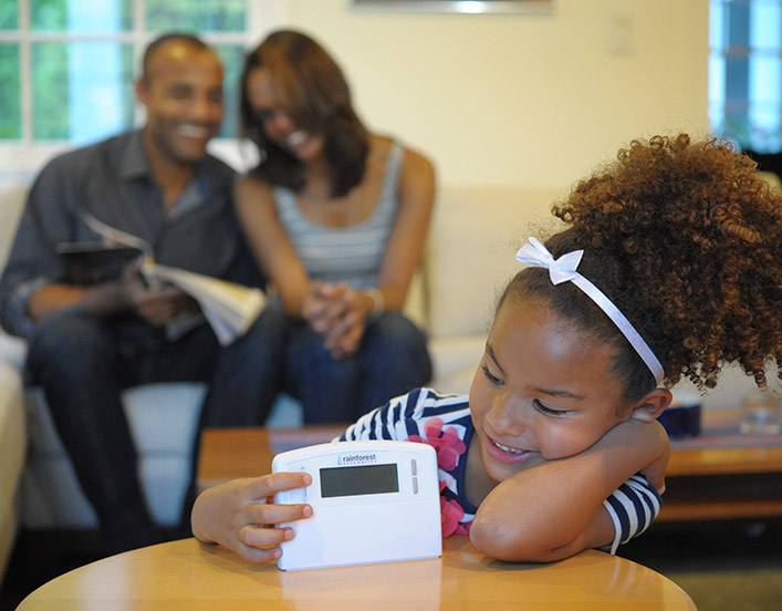 family with child holding smart thermostat