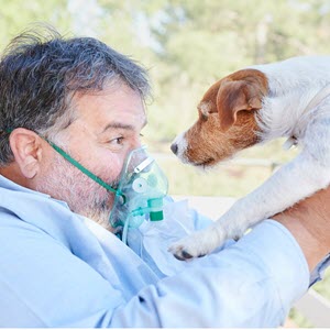 man wearing oxygen mask holding his service dog